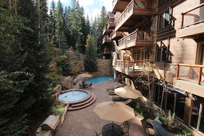A hotel courtyard with a swimming pool, outdoor seating, and a stone wall. - Timbers 3076 (Keystone)