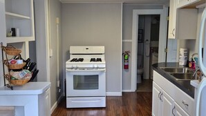 A kitchen with a white stove, wooden flooring, and white cabinetry. - Walk to Lake • Strip • Wineries • Firepit (Geneva)