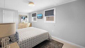 Un dormitorio con cama, cómoda, espejo y ventana con vistas.