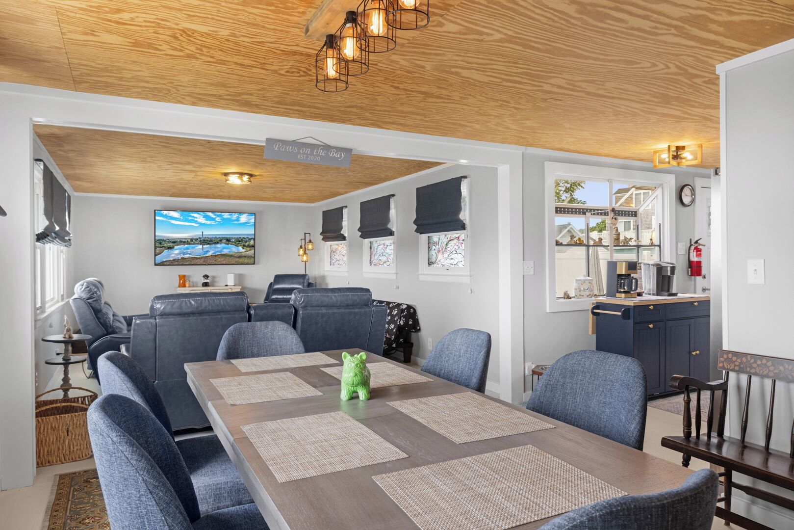 A modern living room with a dining table, sofas, and a kitchen area.