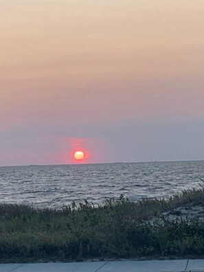 Un atardecer sobre el océano con un barco lejano en el horizonte.