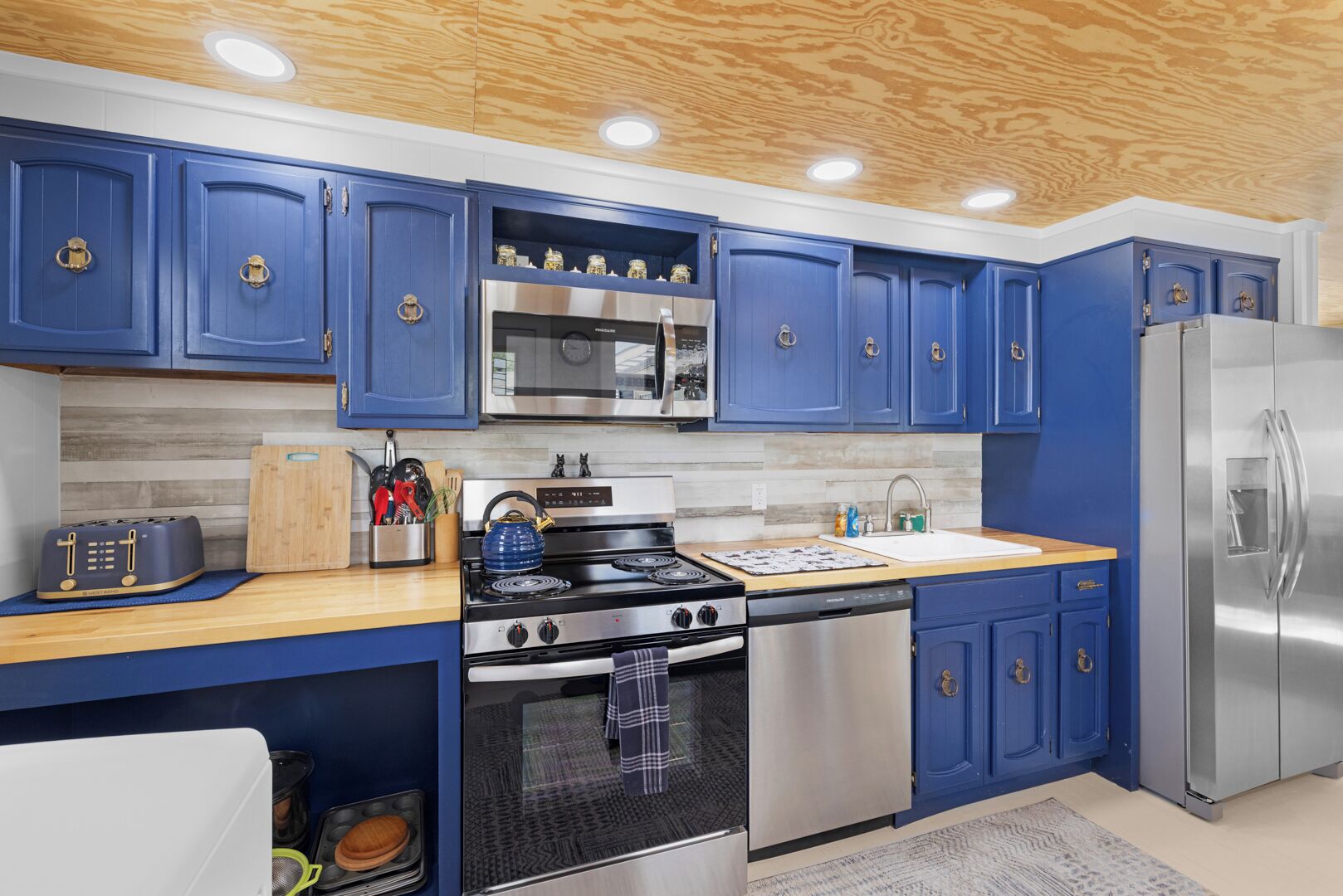 Una cocina moderna con gabinetes azules, electrodomésticos de acero inoxidable y una encimera de madera.