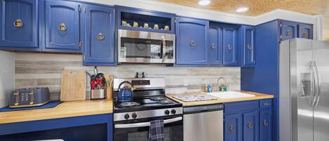 Una cocina moderna con gabinetes azules, electrodomésticos de acero inoxidable y una encimera de madera.