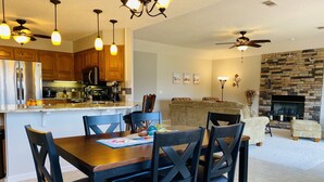 A modern kitchen with wooden cabinets, a built-in oven, and a dining area with a wooden table and chairs. - Spoil yourself with this beautiful Lake Balboa retreat (Hot Springs Village)