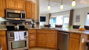 A kitchen with wooden cabinets, stainless steel appliances, a granite countertop, and pendant lighting. - Spoil yourself with this beautiful Lake Balboa retreat (Hot Springs Village)