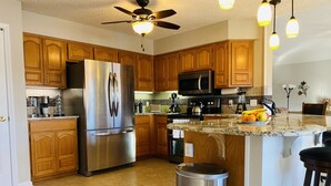 A modern kitchen with wooden cabinets, stainless steel appliances, a granite countertop, and a ceiling fan. - Spoil yourself with this beautiful Lake Balboa retreat (Hot Springs Village)