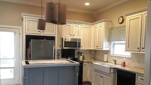 A kitchen with white cabinetry, a central island with stools, a refrigerator, a microwave, and a dishwasher. - Luxury Escape close to Pinnacle Hills Promenade (Rogers)