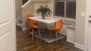 A dining area with a white table, orange chairs, a potted plant, and a window with blinds. - Luxury Escape close to Pinnacle Hills Promenade (Rogers)