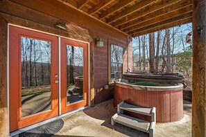 Une cabane en bois avec un jacuzzi et une véranda couverte.