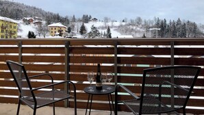Ein Balkon mit zwei Metallstühlen, einem kleinen runden Tisch, einer Weinflasche und zwei Weingläsern.