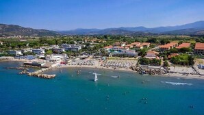 An aerial view of a coastal town with buildings, a beach, and clear blue waters. - Hotel Il Tempio (Casal Velino)