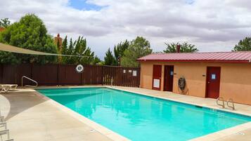 Relax by the clear pool surrounded by a deck and lounge chairs.