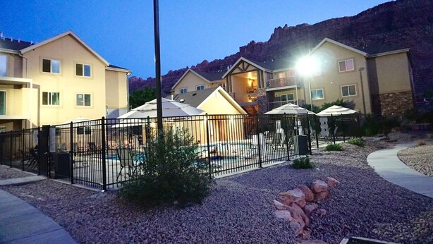 A residential area with multiple houses, a fenced pool area, and a mountain backdrop. - Moab Oasis Entire Condo (Moab)
