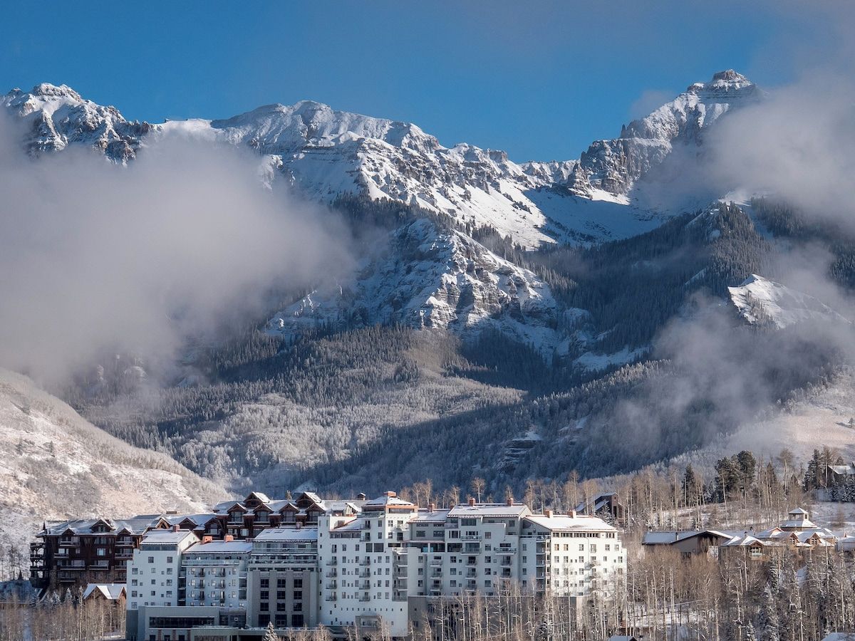 A mountain resort with snow-covered peaks and a cluster of buildings in the foreground.