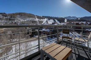 A balcony with a view of a snowy mountain landscape and a ski resort.