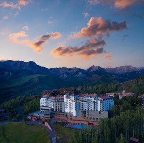 A hotel complex with multiple buildings, surrounded by mountains and trees.