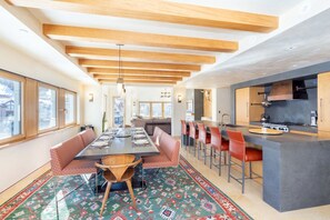 Una cocina moderna con una isla central, asientos tipo bar y un área de comedor con alfombra estampada.