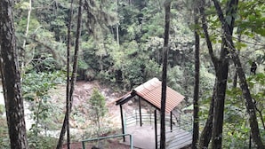 Metsäinen alue, jossa on pieni huvimaja ja portaikko, joka johtaa ylös huvimajaan.