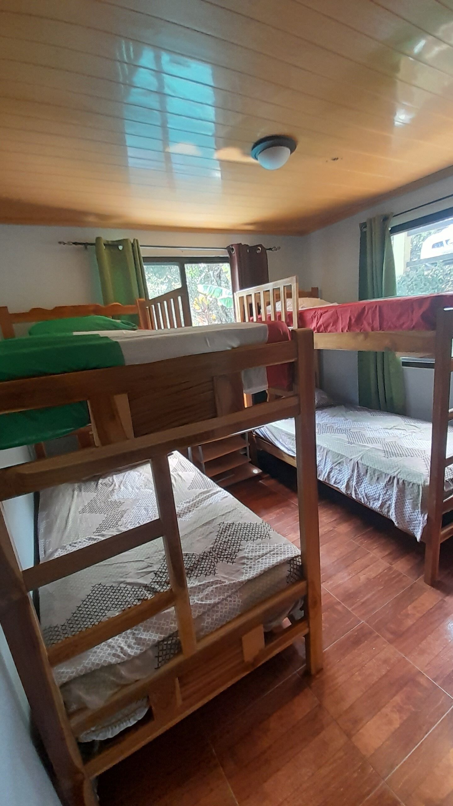 A bunk bed room with wooden frames and a ceiling fan.