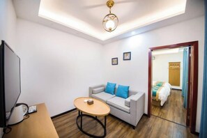 A compact room with a sofa, a small table, a television, and a ceiling light fixture. - Guilin Eiffel Hotel (Xiangbishan Liangjiang Sihu Branch) (Guilin)