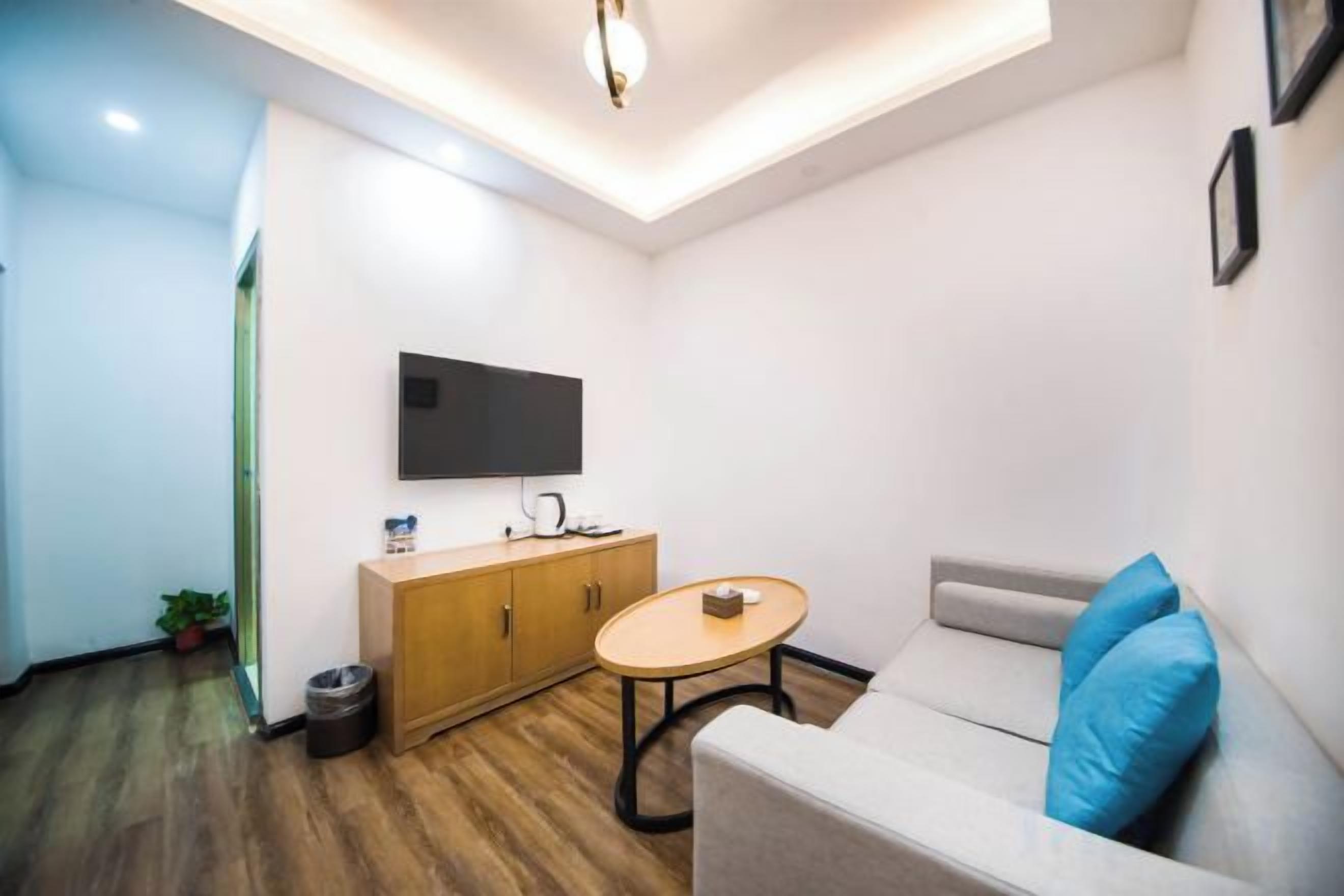 A modern living room with a sofa, a television mounted on the wall, a wooden cabinet, and a small round table.