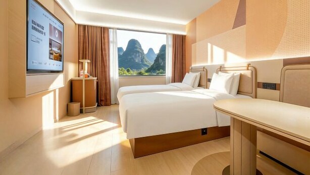Ein Hotelzimmer mit zwei Betten, einem Fernseher, einem Schreibtisch und einem Fenster mit Blick auf die Berge.