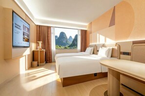 A hotel room with two beds, a TV, a desk, and a window with a mountain view. - Guilin Eiffel Hotel (Xiangbishan Liangjiang Sihu Branch) (Guilin)