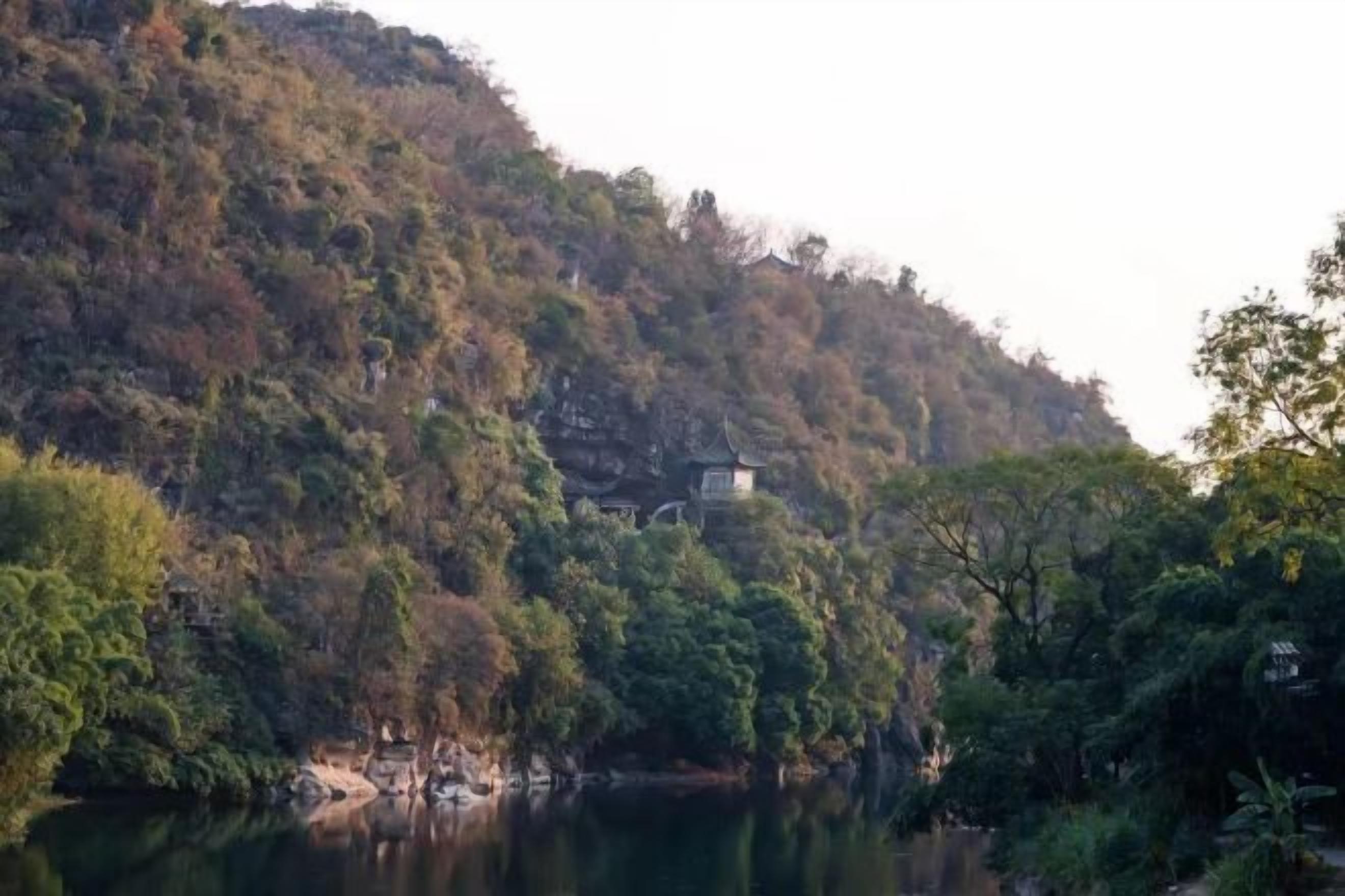 A serene lakeside view with a building nestled among trees.