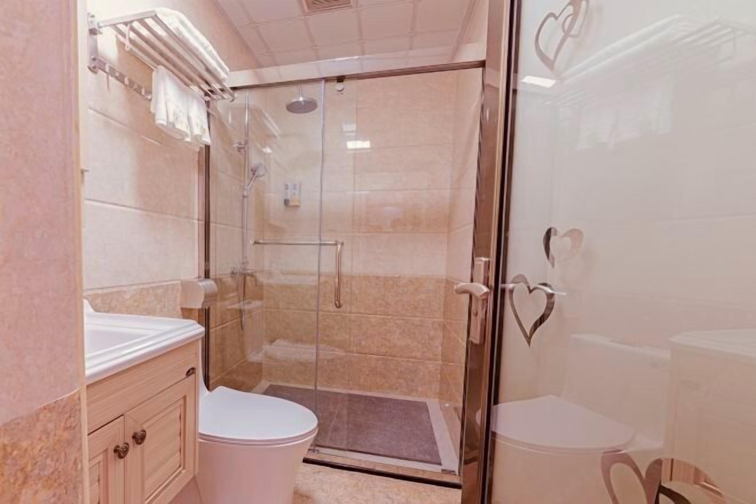 A bathroom with a glass-enclosed shower, a toilet, and a vanity with a towel rack.