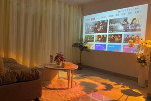 A living room with a couch, a coffee table, and a large screen displaying a video interface. - Guilin Eiffel Hotel (Xiangbishan Liangjiang Sihu Branch) (Guilin)