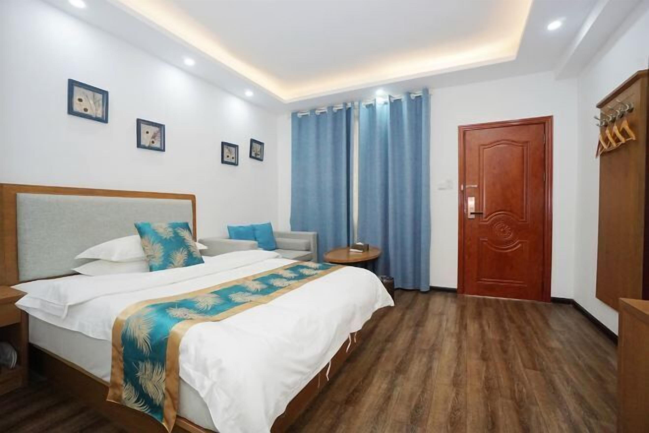 Ein Hotelzimmer mit Bett, Nachttisch, Schreibtisch, Kleiderschrank und einer Tür.