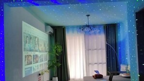 Ein Raum mit projiziertem Bildschirm, einem Blumentopf, einem Sofa und einer Deckenleuchte.