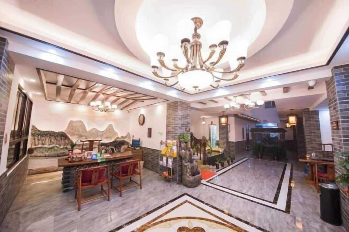Um saguão de hotel com balcão de recepção, área de estar e um candelabro.