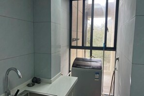 A small, clean bathroom with a white sink, a mirror, and a window with metal bars. - Guilin Eiffel Hotel (Xiangbishan Liangjiang Sihu Branch) (Guilin)