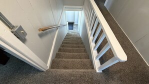 A carpeted staircase with white railings and a handrail, leading to an upper floor.