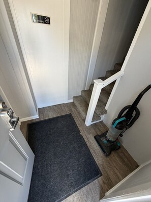 A stairway with a doormat, a vacuum cleaner, and a no-smoking sign. - On The Strip • Cozy GOTL Vacation Cottage (Geneva)