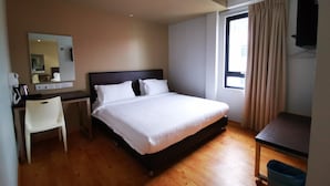 A hotel room with a bed, a desk, a chair, a mirror, an air conditioning unit, and a window with curtains. - D'green Hotel Kuching (Kuching)