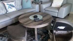 A living room with a grey sofa, two armchairs, a coffee table, and a rug. - Beachfront condo with intracoastal views in Tampa Bay area, heated-cooled pool! (Indian Rocks Beach)