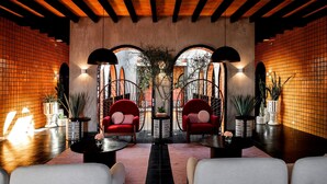 Ein modernes Interieur mit Holzbalkendecke, roten Stühlen, weißen Sofas und Blumentöpfen.