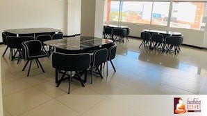 A conference room with a large oval table and multiple chairs, large windows with a city view, and a logo for Buddha Resort Hotels. - Hotel Budhha Resort (Bogotá)
