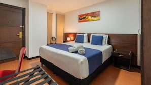 A hotel room with a large bed, a bedside table, a chair, and a painting on the wall. - Hotel Budhha Resort (Bogotá)