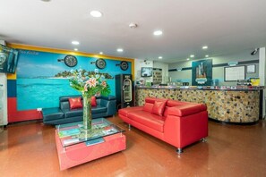 A hotel lobby with a reception desk, two sofas, a coffee table, and a decorative wall with clocks and a floral painting. - Hotel Budhha Resort (Bogotá)