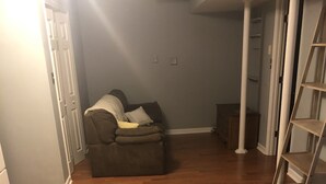 A room with hardwood flooring, a grey sofa, and a white ladder. - Travel Nurses (Madison Heights)