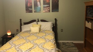 A bedroom with a bed, a nightstand, a wall-mounted shelf, and a rug. - Travel Nurses (Madison Heights)