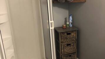 A shower enclosure with a glass door, a toilet, and a shelf with rolled towels.