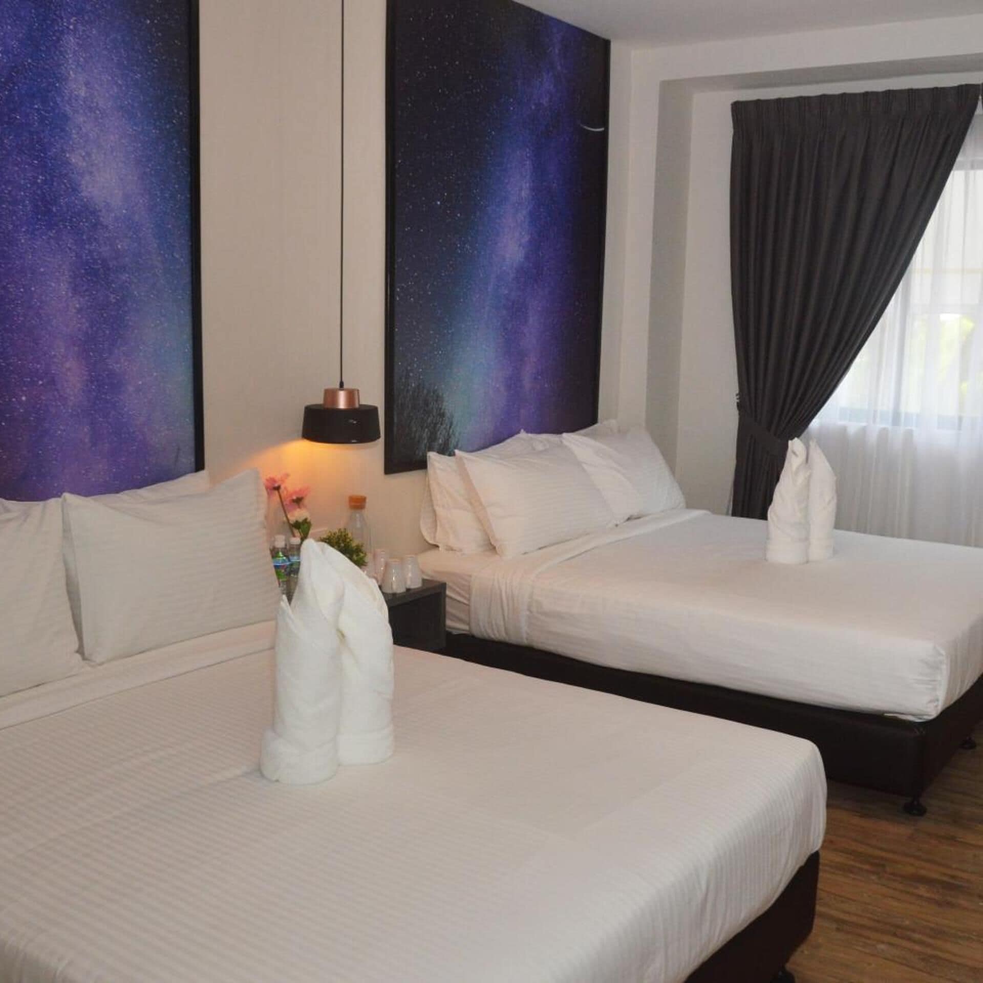 A hotel room with two beds, a nightstand, a lamp, and a large wall painting.