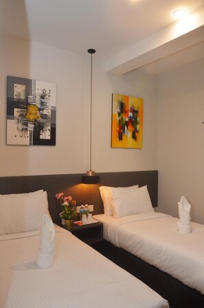 Une chambre d’hôtel avec deux lits, une table de chevet, une lampe et deux œuvres d’art accrochées au mur.