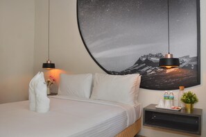 A neatly made bed with pillows, a bedside table with a water bottle, a small plant, and a wall-mounted picture. - De Luna Hotel Sri Petaling (Kuala Lumpur)