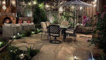 An outdoor patio with stone flooring, wicker furniture, and a fire feature.