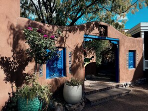 A traditional stucco building with a blue door and windows, surrounded by potted plants and a stone pathway. - Elliot Barker Estate for Large Groups Stroll to Canyon Rd & Plaza (Santa Fe)